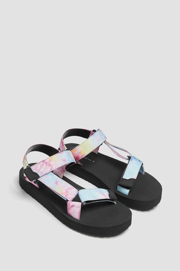 Estas sandalias planas con tiras con estampado tie dye cuentan con cierre mediante tiras adherentes y tienen un precio rebajado de 15,99 euros (antes 19,99 euros).