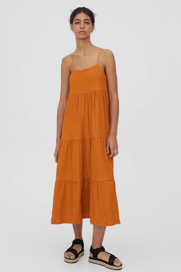 Este vestido naranja de corte midi y tirantes cuenta con volantes y tiene un precio rebajado de 15,99 euros (antes 22,99 euros).