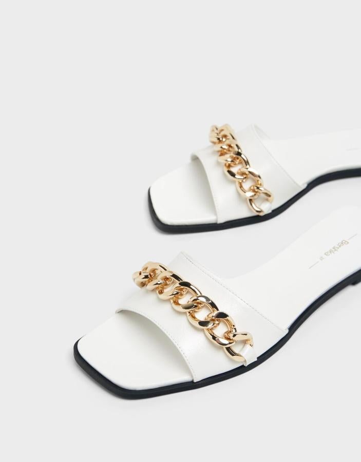 En color blanco con suela en negro, estas sandalias con cadena dorada en el empeine y punta cuadrada podemos encontrarlas entre los números 35 y 41 y de 22,99 euros han pasado a costar 12,99 euros. 