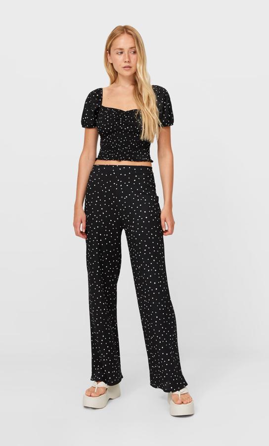 Diseño palazzo para este pantalón de tiro alto de Stradivarius con cintura elástica y perneras anchas que ha llegado a las tiendas en blanco o en negro con estampado de puntos a contraste. Tienen un precio de 17,99 euros y podemos encontrarlos entre las tallas XS y XL.