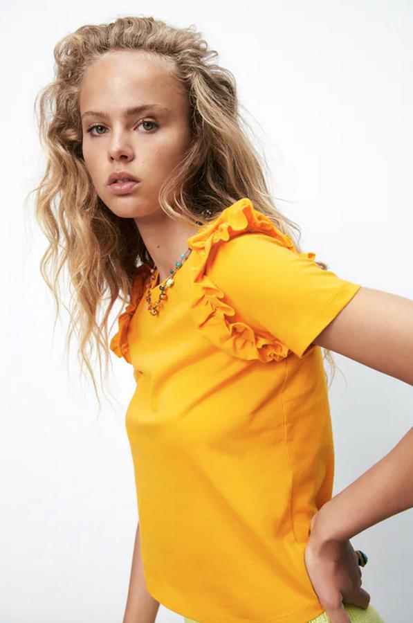 Disponible en cinco colores diferentes, entre ellos el naranja, el blanco o el azul, esta camiseta de cuello redondo y mangas cortas viene con detalle de volantes combinados a tono en los hombros y cuesta 5,95 euros. Podemos encontrarla en las tallas S, M y L.
