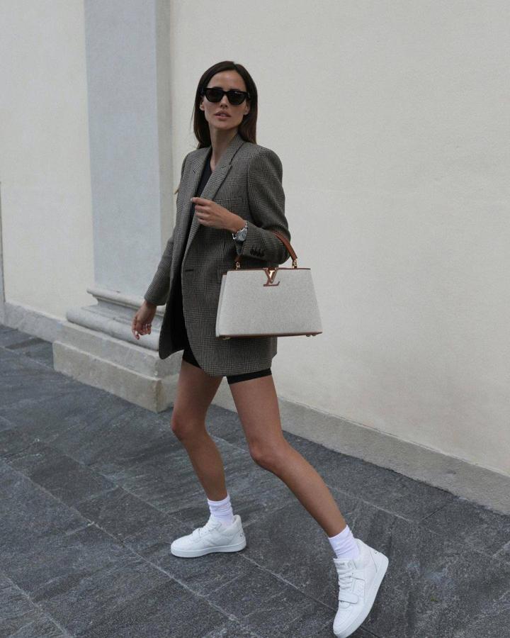 Otra opción para el calor es conjuntar una americana 'oversize' a cuadros con prendas más informales, como mallas de ciclista negras, una camiseta básica sin mangas, ambos en negro. Como calzado, unas deportivas blancas que dejen ver los calcetines.