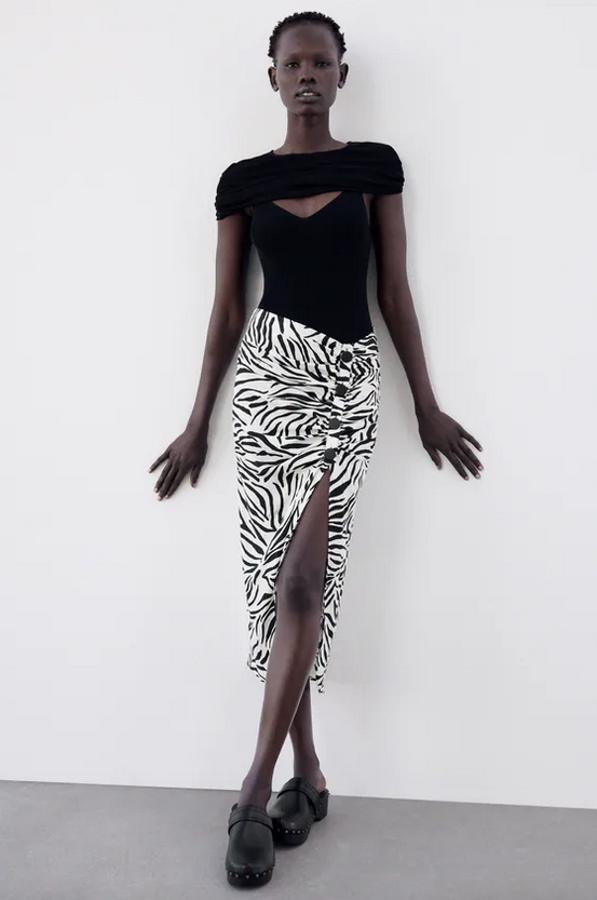 Estampado de cebra en negro sobre fondo blanco para esta falda de Zara confeccionada con viscosa sostenible que viene con detalle de frunces delanteros con falsos botones en negro. El bajo tiene abertura, que queda por encima de la rodilla, y el cierre está en la espalda con cremallera oculta. Con un precio de 25,95 euros, podemos encontrarla entre las tallas XS y XL. 