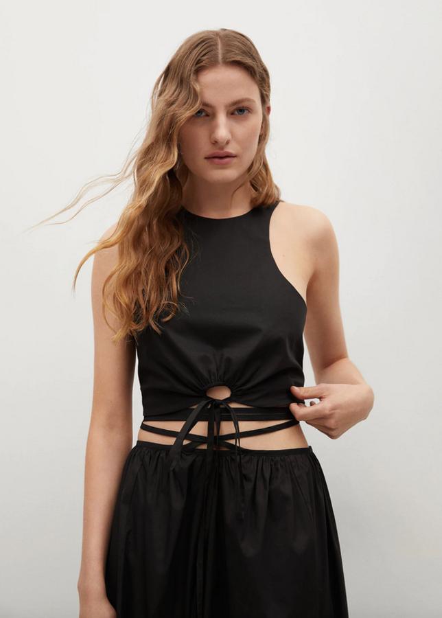 Diseño crop con escote redondo para este top negro de Mango con tirantes finos, cordón decorativo a la cintura y cut-out en el frontal de la cintura. Podemos encontrarlo en las tallas S, M y L por 19,99 euros. 