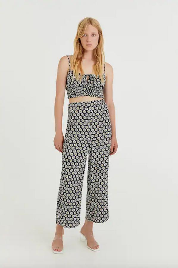 Estampado de margaritas sobre fondo negro para este conjunto de Pull&Bear formado por un top cropped de tirantes finos, con lazada en el pecho y goma canilla en el bajo que cuesta 15,99 euros y unos pantalones culotte de cintura elástica que tienen un precio de 19,99 euros. 