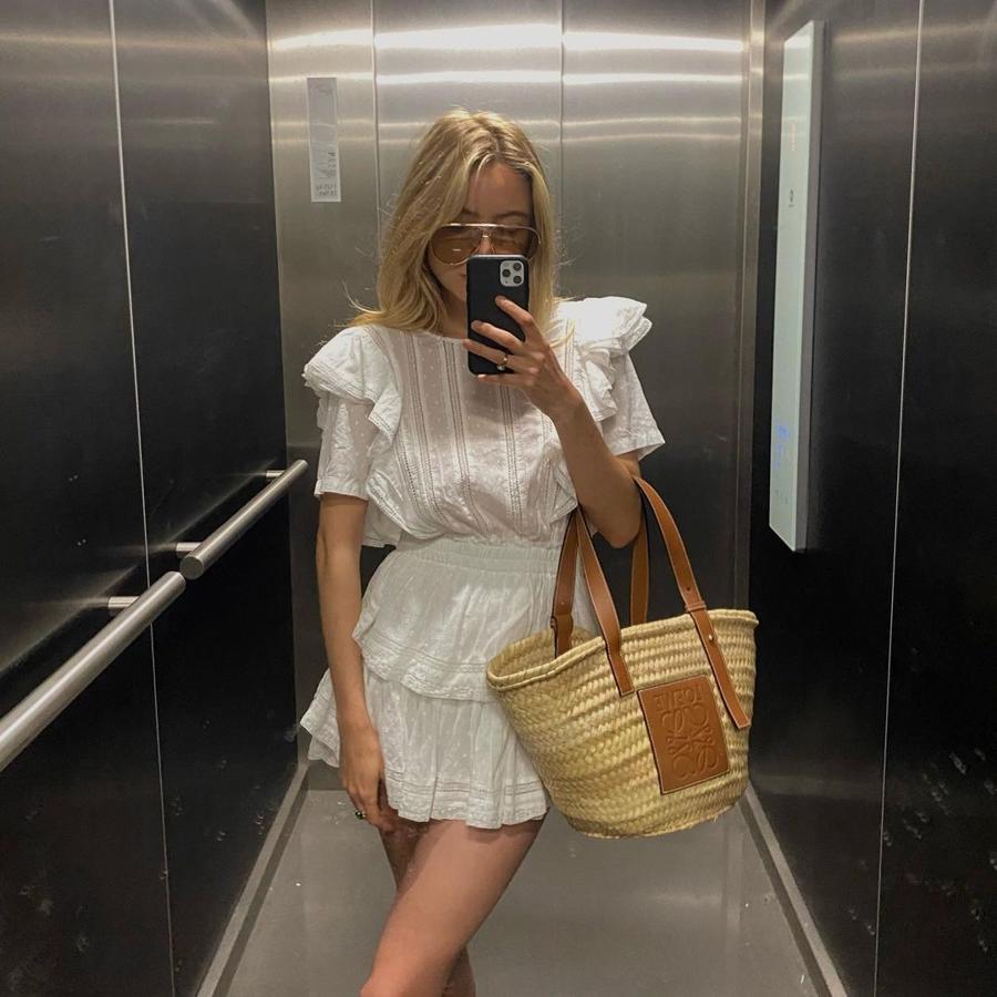 Si nos sentimos románticas y femeninas, un mini vestido vaporoso con bordados, en blanco, es la elección correcta. Conjúntalo con una cesta de rafia y unas gafas de aviador para conseguir la estética 'chic' parisina de esta influencer.