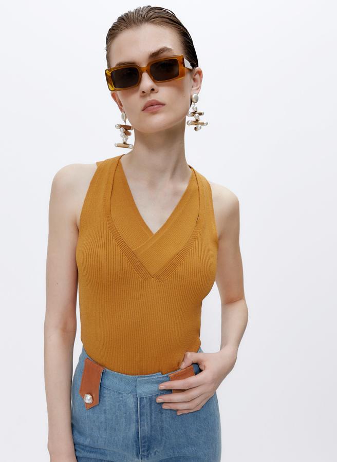 Este top con escote de pico cruzado en canalé de color mostaza tiene un precio rebajado de 29,95 euros.