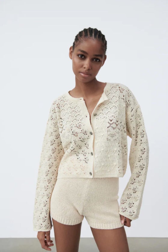 Confeccionado en pointelle con al menos un 40% de algodón reciclado, esta chaqueta en color crudo con cuello redondo y mangas largas viene con cierre frontal de botones joya y cuesta 22,95 euros. Podemos encontrarla entre las tallas S y XL.