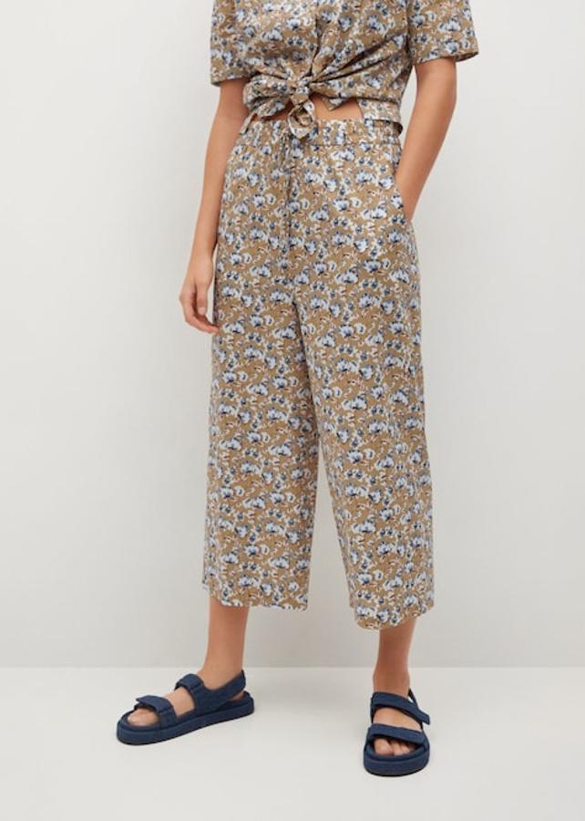 Estampado de flores blancas y azules sobre fondo beige para este pantalón culotte de Mango que viene con cintura elástica con cordón, dos bolsillos laterales y está confeccionado en tejido fluido. Con un precio de 25,99 euros, está disponible entre las tallas XS y L.