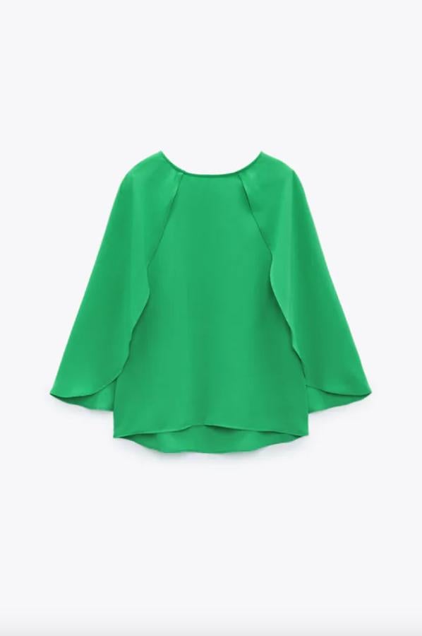Esta blusa verde de Zara viene con cuello redondo y mangas tres cuartos por debajo del codo con diseño tipo capa. Con cierre en la espalda con abertura y botón dorado, podemos encontrarla entre las tallas XS y L por 25,95 euros. 