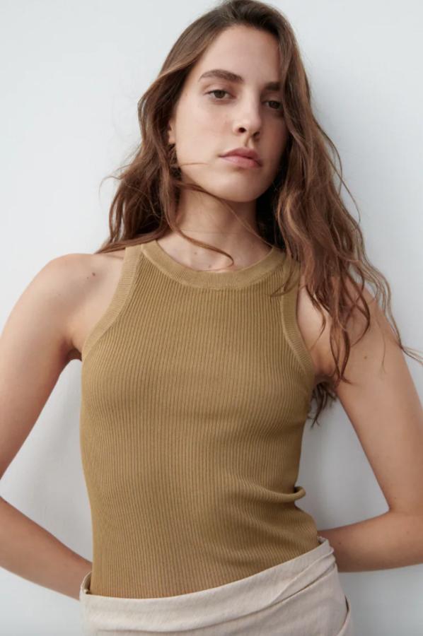 Disponible en camel oscuro, blanco, negro y verde medio, este top de punto con cuello redondo, mangas sisa y acabados en rib tiene un precio de 12,95 euros y está disponible entre las tallas XS y XL. 