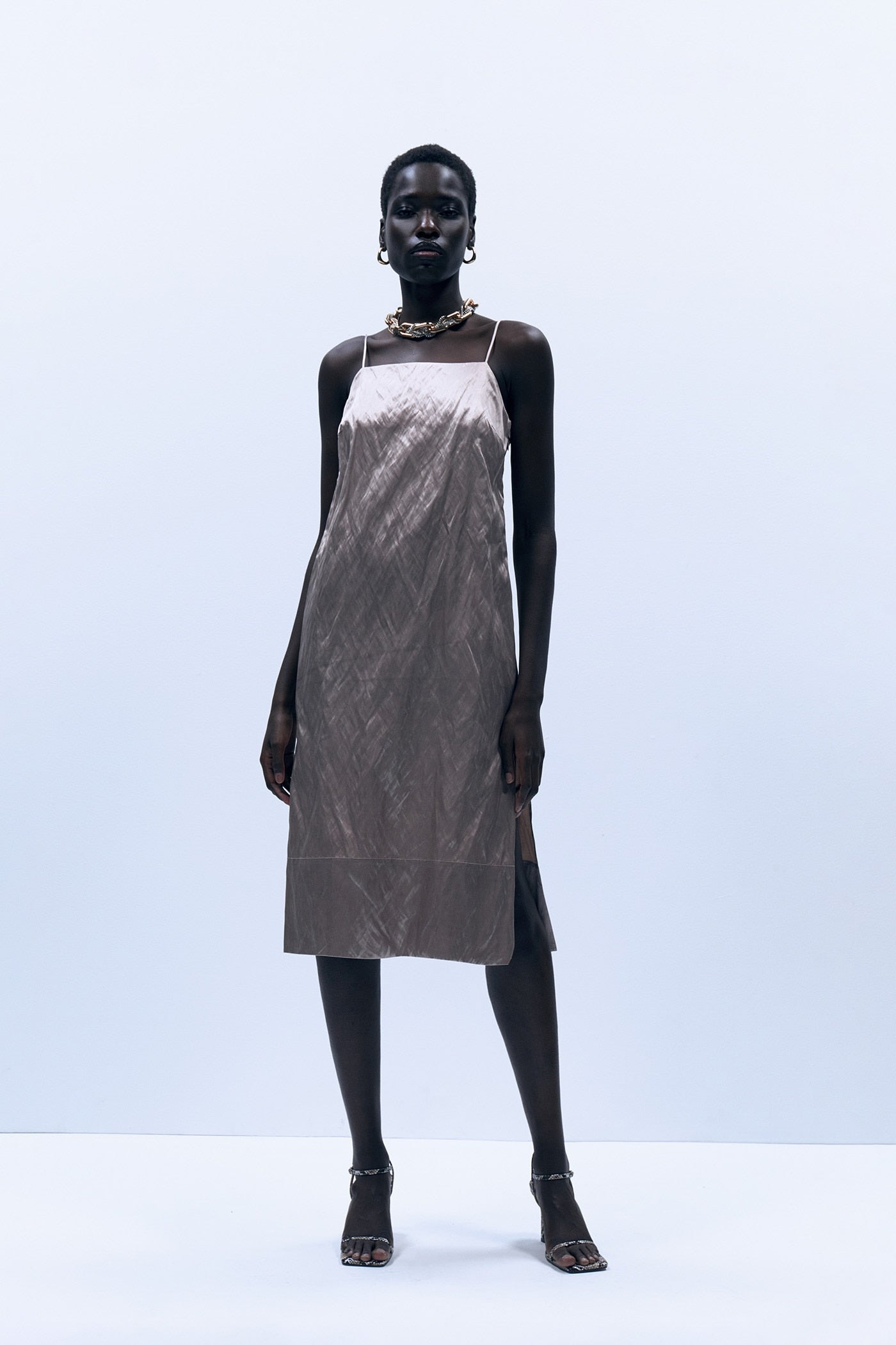 Vestido midi de tirantes con efecto satinado metalizado, de Sfera (19,99 €).