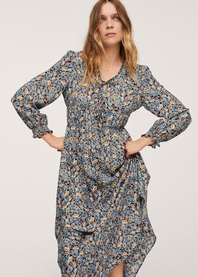 Fondo negro con estampado floral en mostaza, crudo y azul para este precioso vestido de diseño midi acampanado con mangas largas terminadas en puños elásticos y cintura elástica. Con escote de pico con cierre de lazo y confeccionado en tejido fluido, tiene un precio de 29,99 euros y está disponible entre las tallas XXS y XXL. 