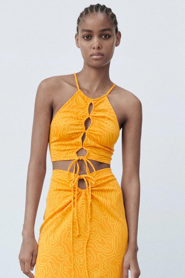 Este top naranja con cuello halter y tirantes finos cuenta con aberturas en la parte delantera y cierre con lazos en el bajo y en la espalda. Tiene un precio de 19,95 euros.