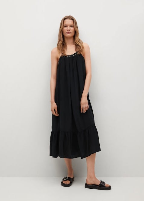 Diseño acampanado para este vestido negro de Mango con escote redondo y tirantes finos que viene con apliques decorativos plateados en el cuello. Con volante en el bajo y detalles plisados, podemos encontrarlo entre las tallas XS y XL por 39,99 euros. 