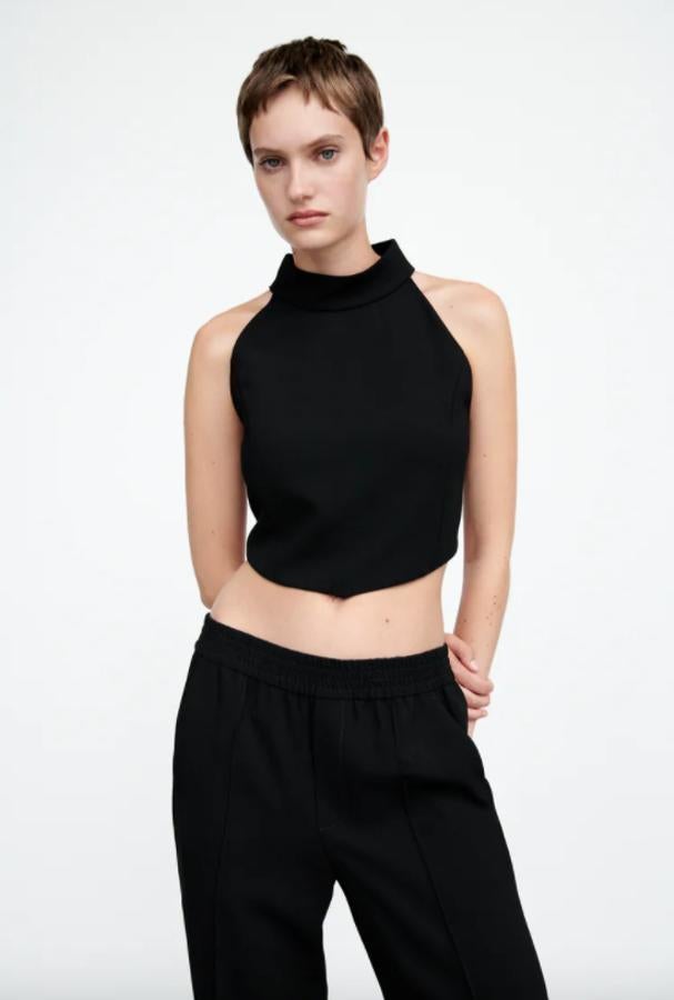 Diseño corto con cuello halter para este top en color negro con bajo asimétrico que cuesta 25,95 euros y podemos encontrar entre las tallas XS y XL.