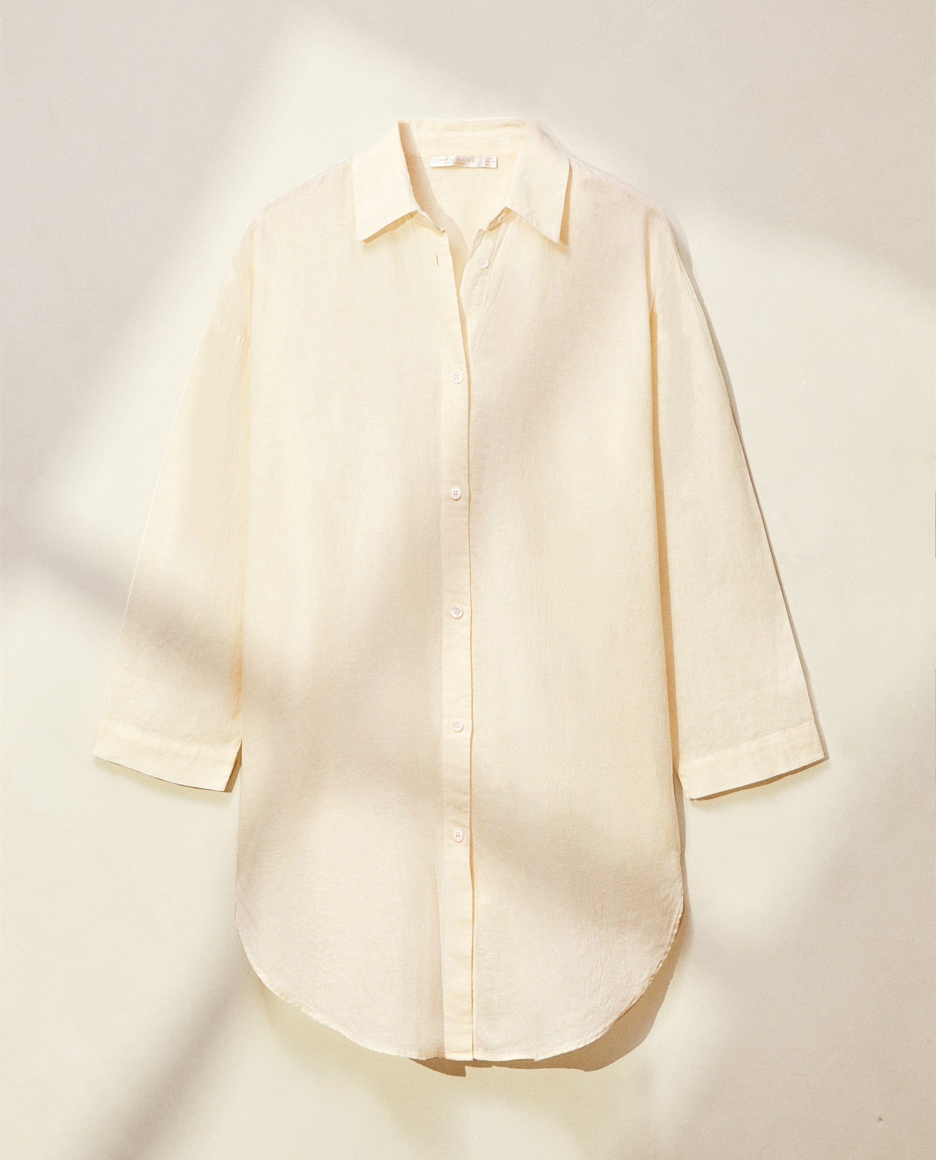 De lino y silueta oversize, esta camisa de estilo masculino en blanco roto puedes llevarla anudada en la cintura con tus vaqueros favoritos, encima de tus vestidos 'slip dress' y vestidos boho... ¡o incluso como minivestido con unas botas! Cuesta 49.99 euros en Zara Home. 