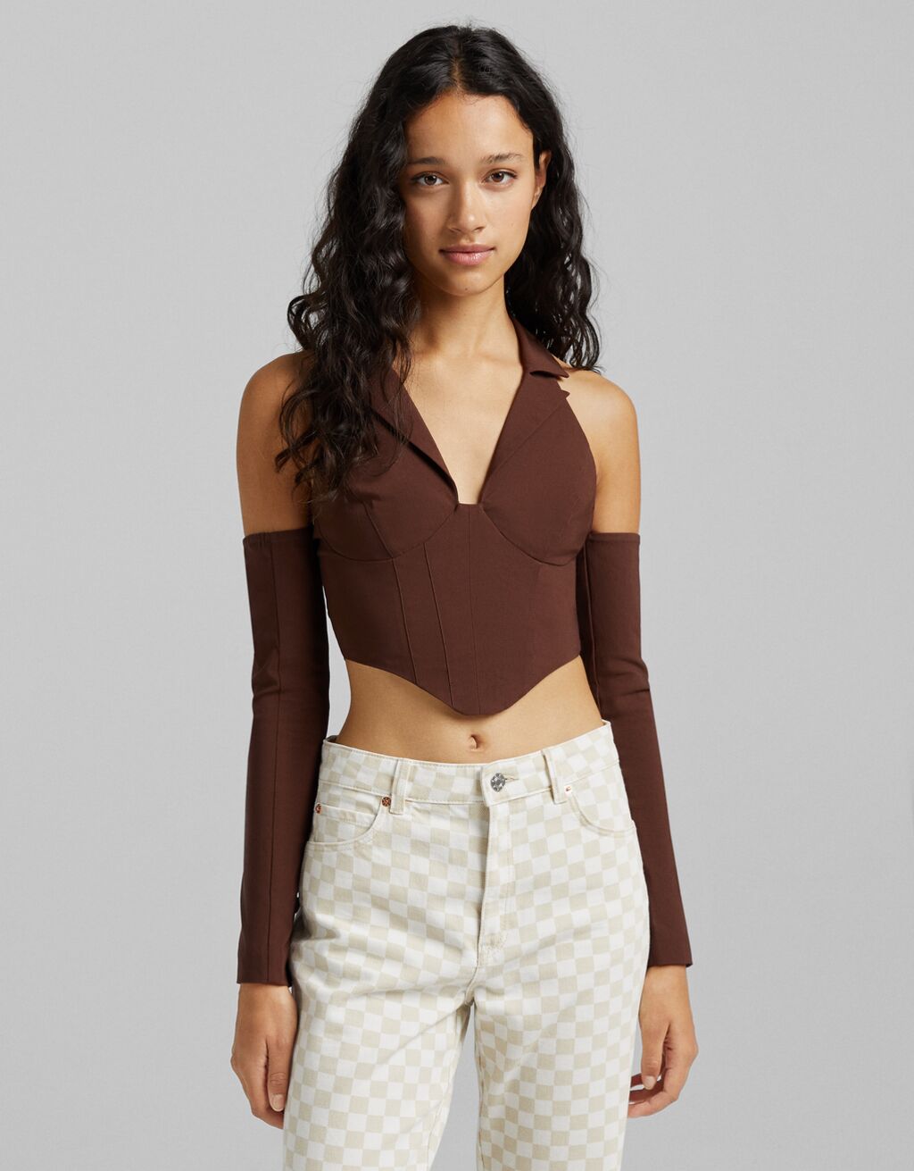 De diseño bustier, con cuello con solapas con muesca y hombros al aire, esta blusa en color marrón con cuerpo anudado en la espalda tiene un precio de 22,99 euros y podremos encontrarla próximamente entre las tallas XS y L.