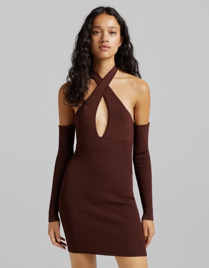 De diseño mini, con escote cruzado y hombros al aire, este vestido de Bershka de talle ajustado y tejido acanalado con espalda al aire tiene un precio de 25,99 euros y está disponible entre las tallas XS y L. 