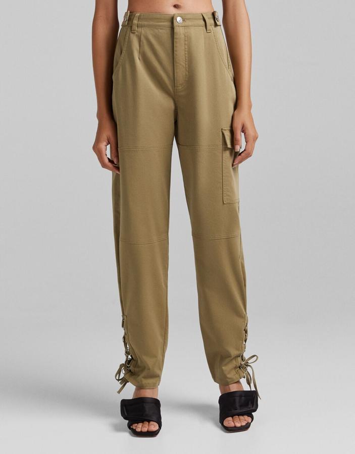 Con aberturas laterales en los bajos que vienen con lazada a tono, este pantalón de algodón en color caqui con bolsillos cargo en las perneras es de Bershka tiene un precio de 35,99 euros y está disponible entre las tallas 32 y 44. 