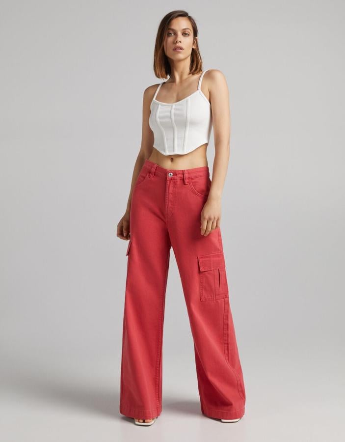 Disponible en rojo, en negro o en crudo, este pantalón de sarga con perneras amplias y bolsillos en los laterales a la altura de las rodillas es de Bershka y cuesta 25,99 euros. Está disponible entre las tallas 32 y 44.