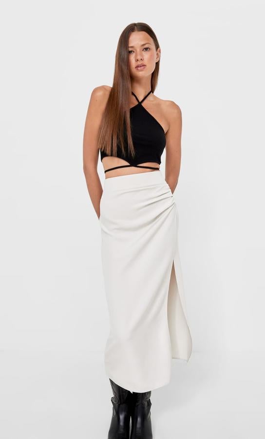 Esta falda midi de tiro alto con frunce lateral y abertura en el bajo es de Stradivarius y podemos encontrarla en color negro, en marrón y en piedra. Cuesta 19,99 euros y está disponible entre las tallas 34 y 44.