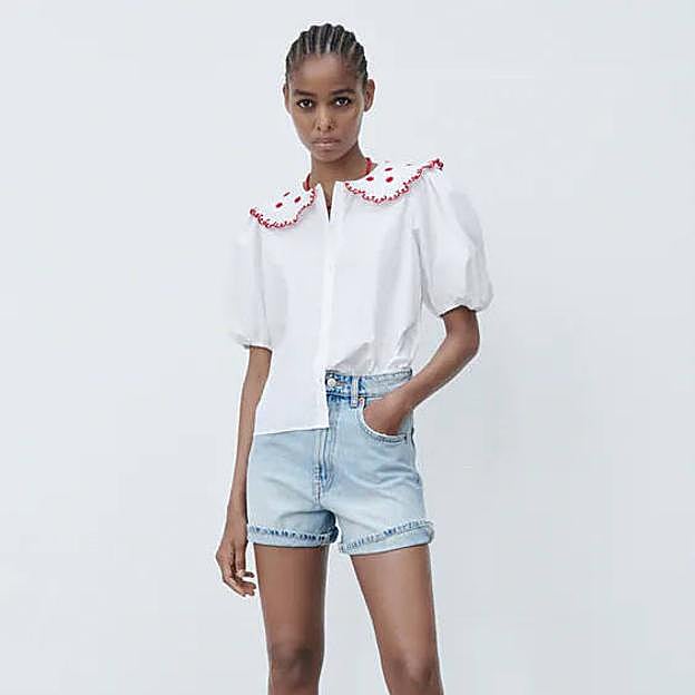 La camisa de popelín es de color blanco con bordados en rojo