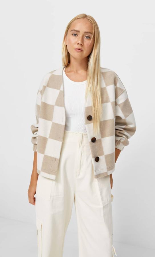 Diseño de damero en blanco y beige medio para este cárdigan de Stradivarius con cuello caja y mangas largas que tiene cierre frontal de botones a contraste. Cuesta 25,99 euros y está disponible entre las tallas XS y XL.