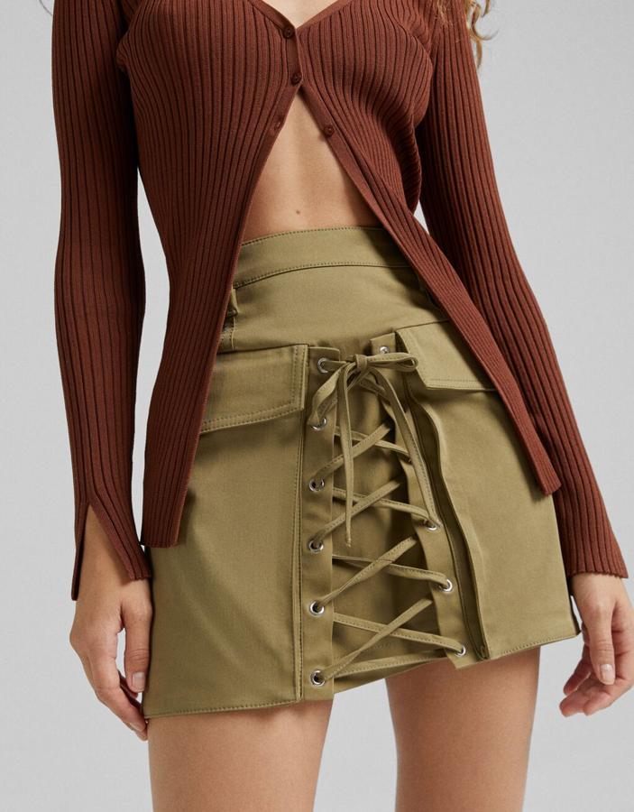 Con bolsillos de plastrón con solapa y lazada frontal a tono, esta minifalda caqui de Bershka confeccionada en algodón está disponible entre las tallas XS y XL por 25,99 euros. 