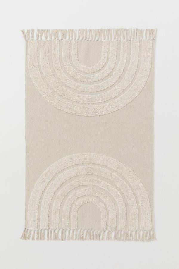 En color blanco, esta alfombra de algodón con flecos y arcoíris grande en peluche de pelo corto tiene una medida de 90x130 centímetros y un precio de 39,99 euros.