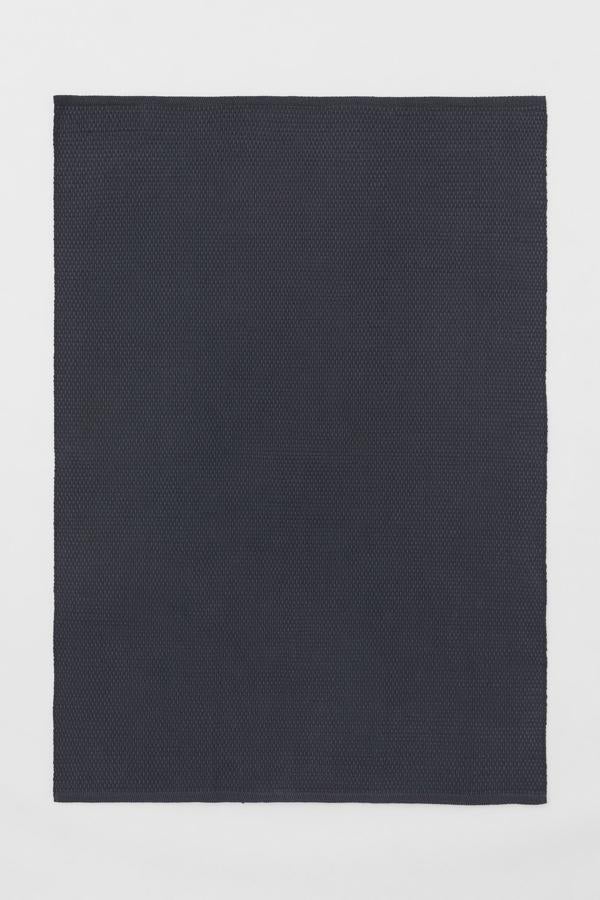 Disponible en gris oscuro o en beige, esta alfombra de algodón con textura mide 140x200 centímetros y tiene un precio de 99 euros.