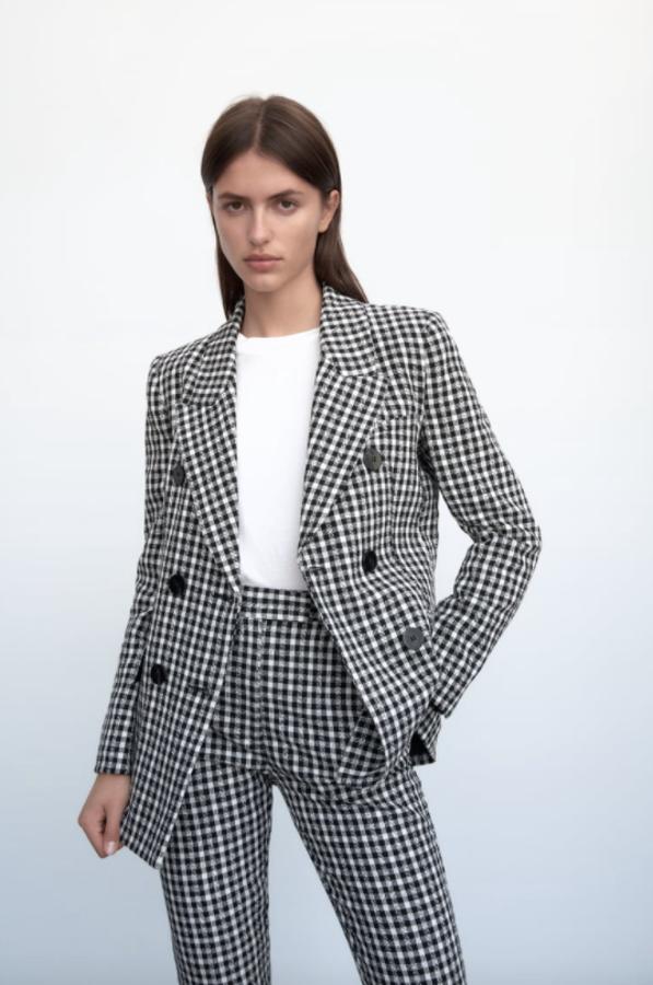 Con cuello de solapa con muesca y mangas largas, esta blazer de Zara con estampado de cuadro vichy en blanco y negro viene con bolsillos delanteros con solapa y cierre frontal con botones negros. Cuesta 49,95 euros y está disponible entre las tallas XS y XL. 
