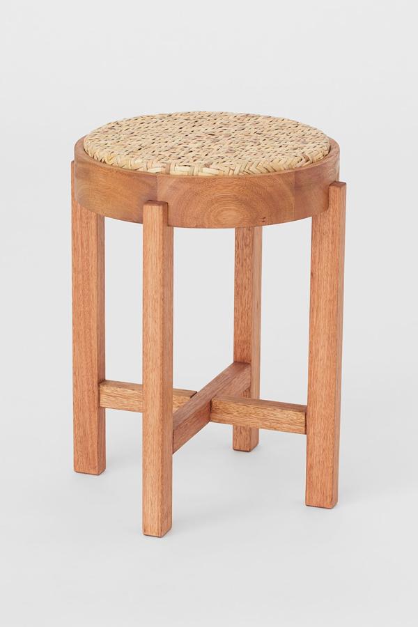 Disponible en beige o en negro, este taburete redondo en madera de eucalipto con asiento de ratán trenzado tiene un diámetro de 31 centímetros y una altura de 43,5. Su precio es de 79,99 euros.