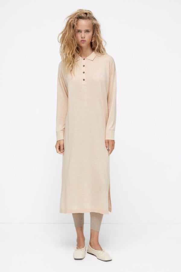 De color beige, este vestido de punto de manga larga y cuello solapa cuenta con bajo con aberturas laterales y cierre frontal con botones. Tiene un precio de 29,95 euros.