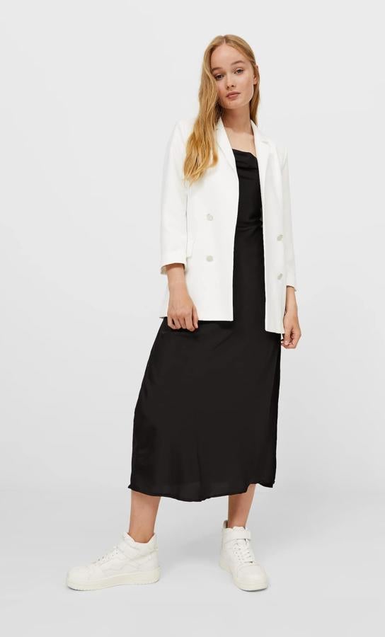 Diseño abierto para esta americana de Stradivarius que podemos encontrar en color blanco o en negro y viene con falsa botonadura metalizada en el frontal. Con mangas tres cuartos acabadas en vuelta y cuello de solapa con muesca, tiene un precio de 29,99 euros y está disponible entre las tallas XS y XL. 