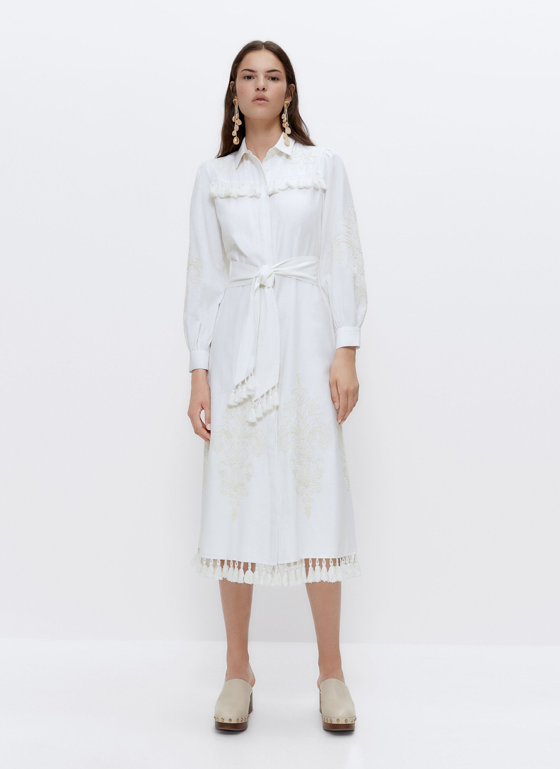 ¿Puede ser más especial este vestido camisero blanco con bordados y rematado con borlones? Cuesta 129 euros en Uterqüe.