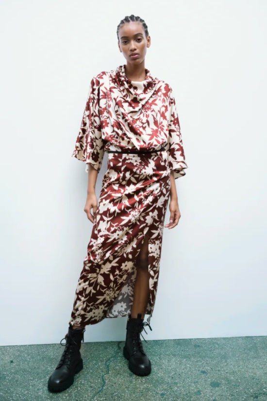 Estampado floral en blanco sobre fondo marrón para esta falda midi de tiro alto con frunces laterales en la cintura y bajo con abertura frontal. Es de Zara, cuesta 29,95 euros y está disponible entre las tallas XS y XL. 