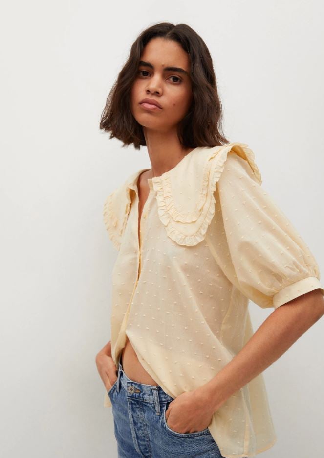 Esta blusa de plumeti en amarillo vainilla con cuello bobo pondrá un toque muy romántico a tus looks de entretiempo. Está rebajada en las mid season de Mango a 19.99 euros.