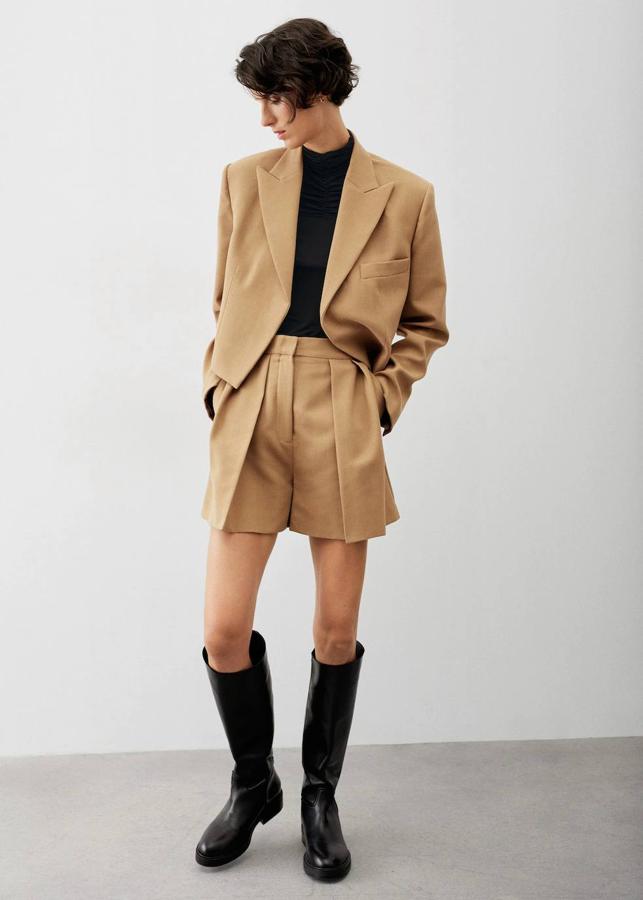 Shorts fluidos con detalle de pinzas, 29,99 euros. Americana crop con ribete, 69,99 euros. Jersey negro, 9,99 euros. Botas altas de piel planas, 119,99 euros.