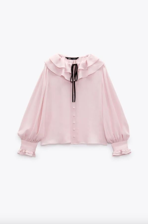 Esta blusa es tan bonita que no nos hemos podido resistir a incluirla en esta selección. En color rosa claro, con cuello con volantes y lazo combinado a contraste en negro, también tiene volantes en los puños y detalle de falsos botones delanteros forrados a tono. Podemos encontrarla entre las tallas XS y XL y cuesta 25,95 euros. 