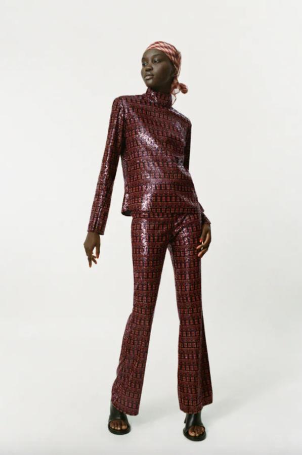 Estampado geométrico en tonos anaranjados sobre fondo negro para este pantalón de lentejuelas de tiro alto con bajo acabado en línea evasé que tiene cierre frontal de cremallera y botón. Disponible entre las tallas XS y XXL, tiene un precio de 49,95 euros. 