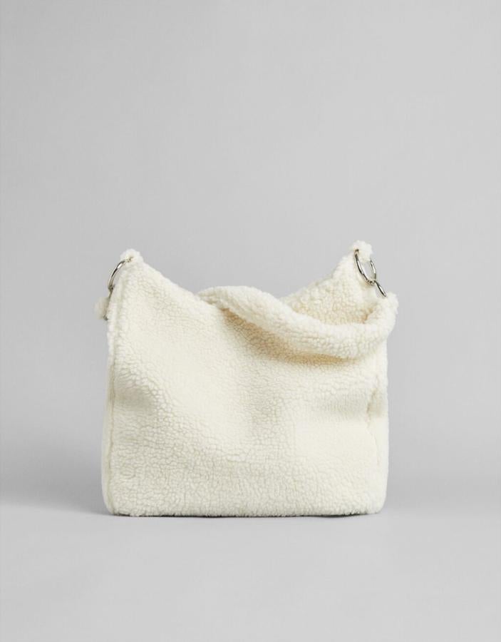 Efecto borrego en color blanco para este bolso de diseño shopper con asa de hombro en el mismo material y anillas metalizadas. Tiene cierre superior de cremallera y cuesta 19,99 euros. 
