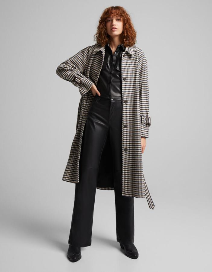 A medio camino entre la gabardina y el abrigo, esta prenda se convertirá en tu mejor aliada para los meses más fríos del año. Un bonito estampado de cuadros y un favorecedor cinturón son sus claves del éxito. Abrigo de Bershka (69,99 euros). 