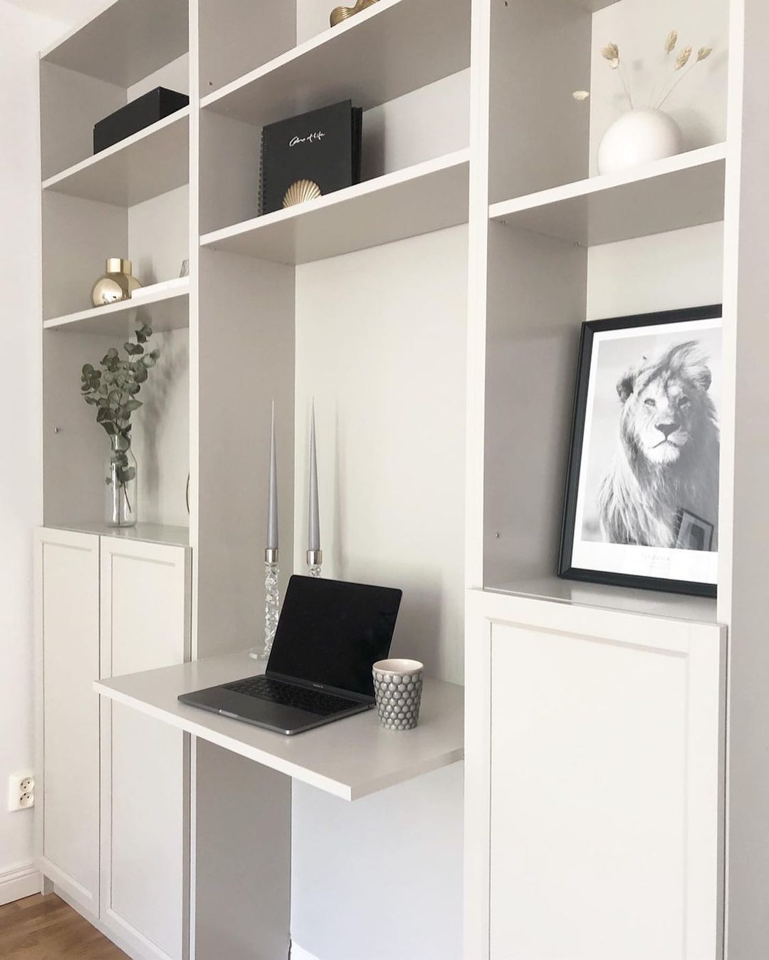 Dos entanterías Billy con puertas en la parte inferior unidas por un sencillo tablero de madera lacado en blanco... y tenemos un despacho elegante montado en un rincón del salón.