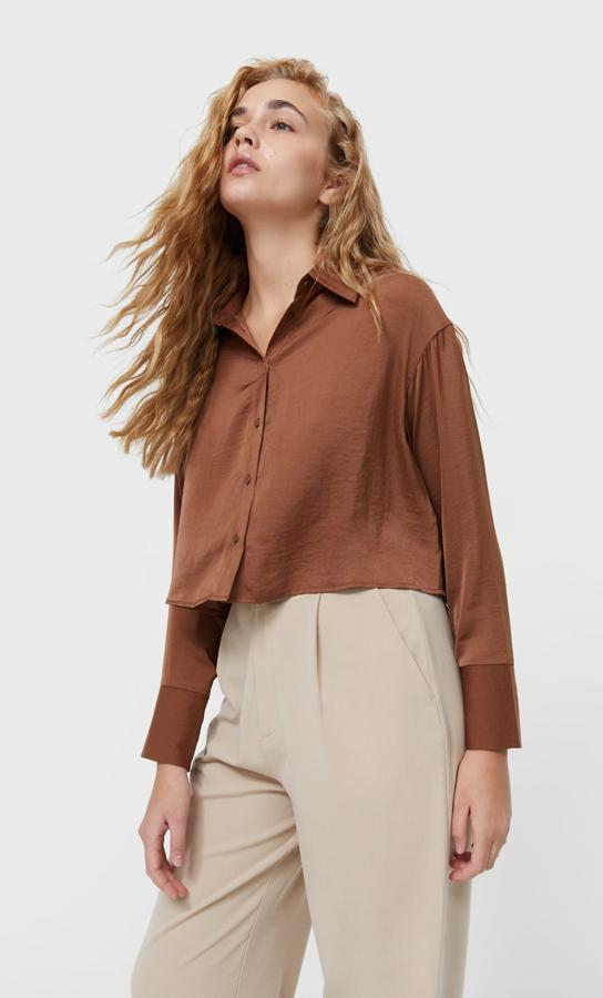 Diseño cropped con cuello de solapa y mangas largas con puño amplio abotonado para esta camisa de Stradivarius disponible en blanco, marrón, negro, malva y caqui que cuesta 17,99 euros y está disponible entre las tallas XS y XL.