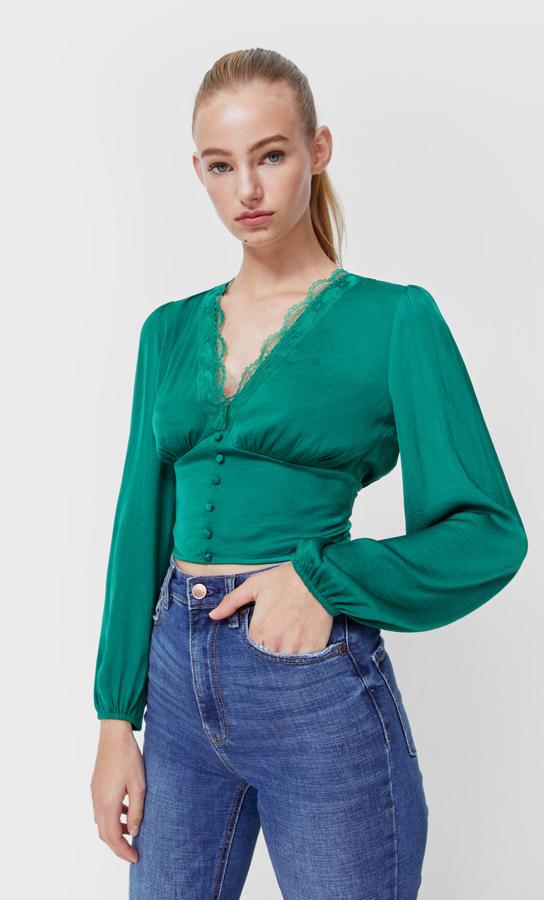 Con escote de pico con detalle de puntilla y mangas largas abullonadas, esta blusa de satén con cierre frontal de botones forrados a tono y cintura ceñida está disponible en cinco colores, entre ellos el verde, el marrón o el negro y cuesta 19,99 euros. Está disponible en Stradivarius entre las tallas XS y XL.