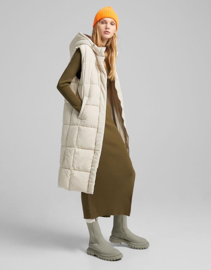 Disponible en arena y en color negro, este chaleco largo puffy de Bershka con bolsillos al bies, mangas sisa y capucha, viene con cierre frontal de cremallera y cuesta 39,99 euros. Está disponible entre las tallas XS y L. 