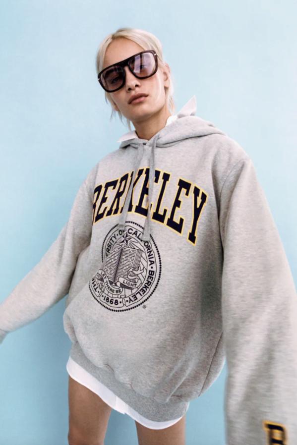 En gris vigoré, con capucha ajustable con cordones y mangas largas, esta sudadera de Zara con detalle de estampación en delantero tipo college cuesta 29,95 euros y está disponible en las tallas S, M y L. 