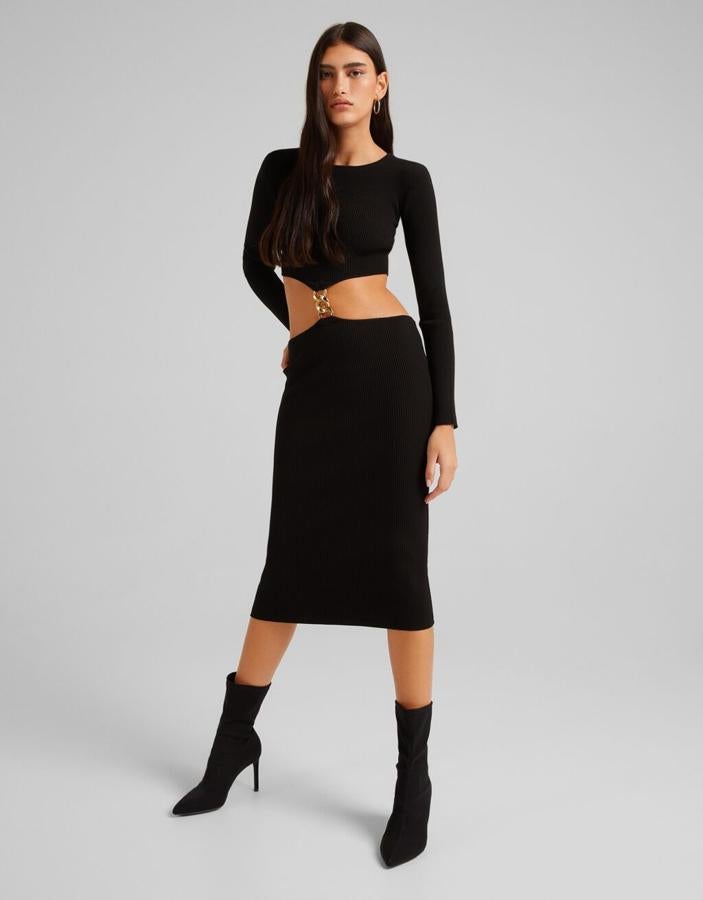 Diseño acanalado para este vestido de dos piezas unidas por cadena dorada gruesa en la cintura. De color negro, con mangas largas y cuello redondo, este vestido Bershka está disponible entre las tallas S y XL por 25,99 euros. 