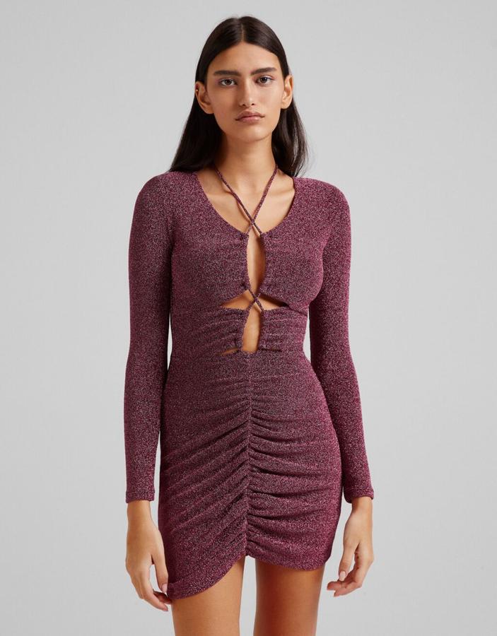 Diseño fruncido en la falda y lazada en el cuerpo atada en la parte posterior del cuello para este vestido mini de Bershka en fucsia con brillos. Disponible entre las tallas XS y XL, cuesta 29,99 euros.